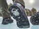 Low angle from behind of Nexgrip boots walking past studded fat bike tire.