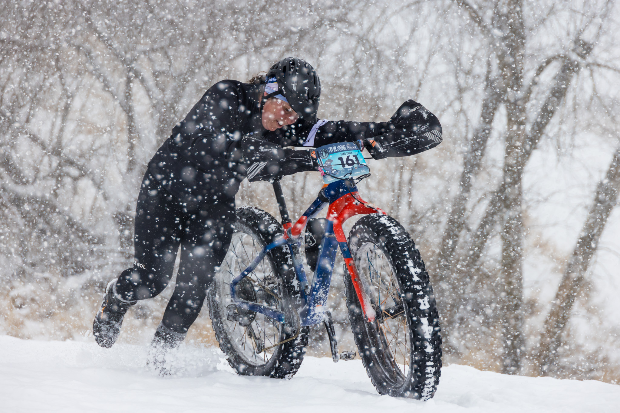 Woman pushing a fat bike in a snowstorm during the US Fat Bike Open race.