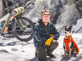Man and dog in snow next to fat bike and waterfall