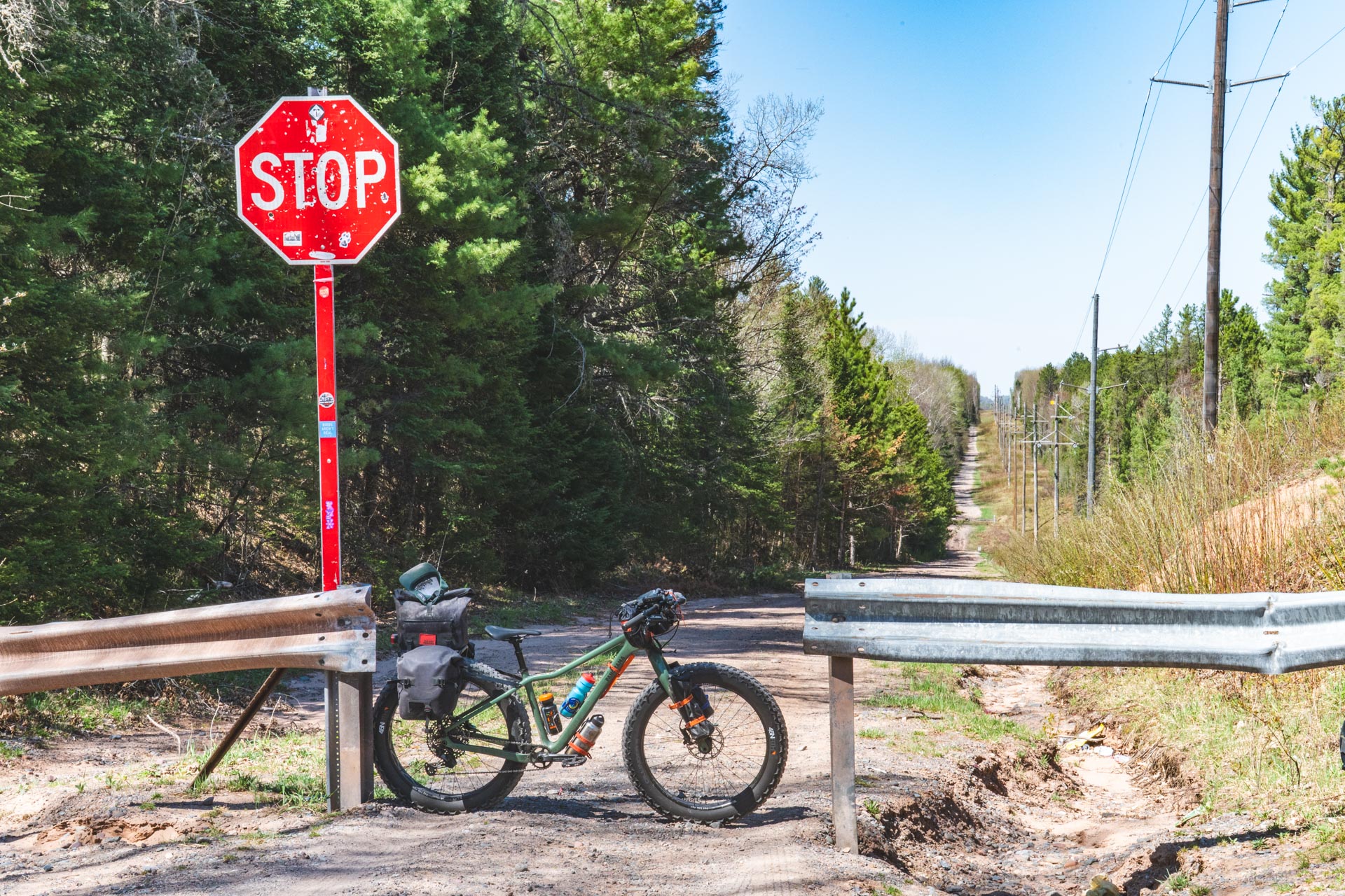fat bike loaded for bikepacking leans agains guard rail on gravel road